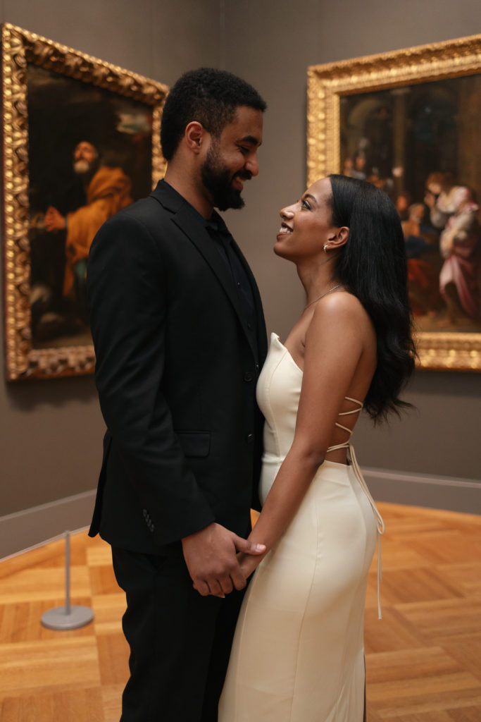 man and woman smiling at each other while looking at art inside of the met