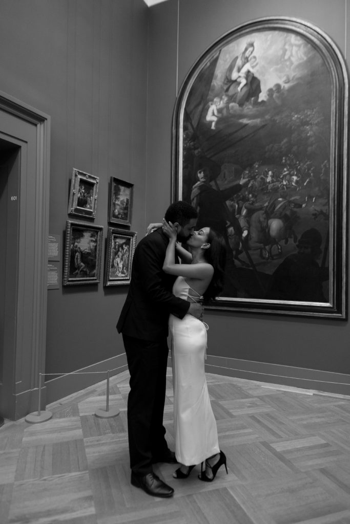 man and woman kissing in front art at the met