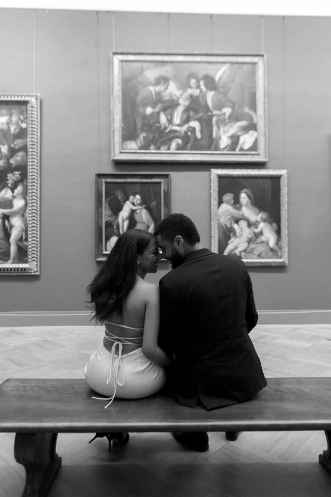 man and woman looking at each other while sitting down in front of art