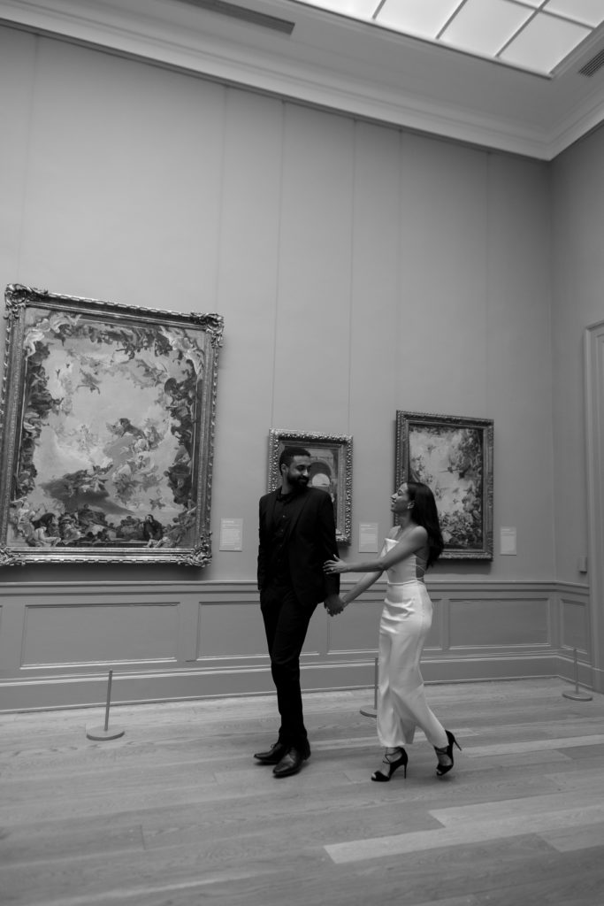 couple engagement photos at the met - woman is holding mans arm while walking in front of art
