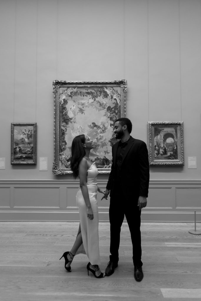 man and woman laughing with each other while looking at art inside the met museum