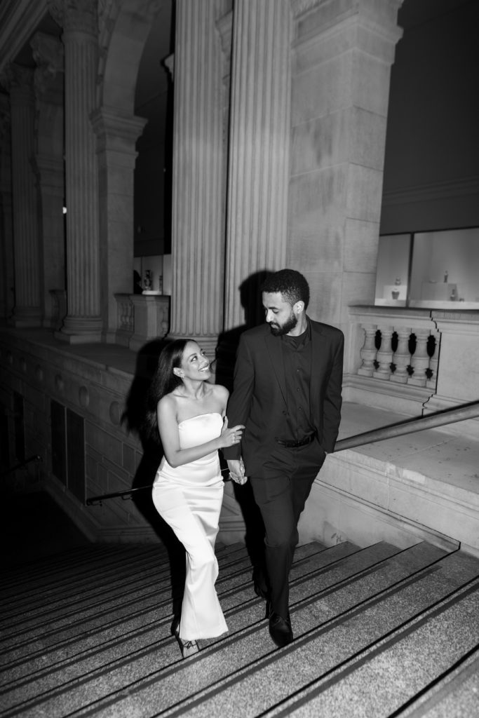 woman holding mans hand while walking up the stairs for their engagement photos