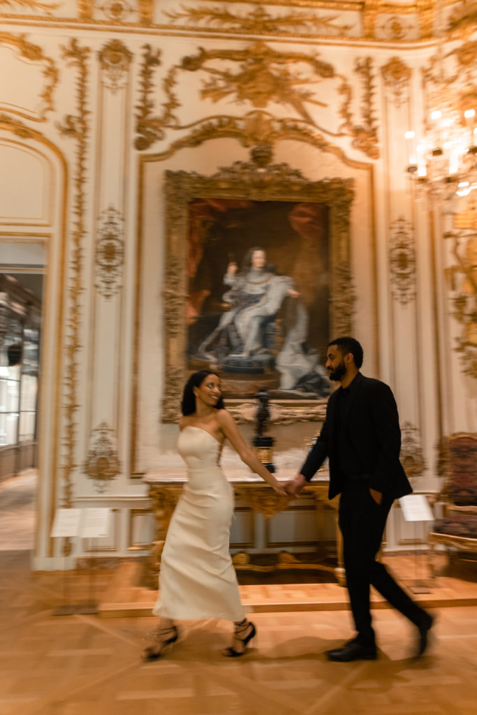 man and woman holding hands while looking at each other and running in the art museum